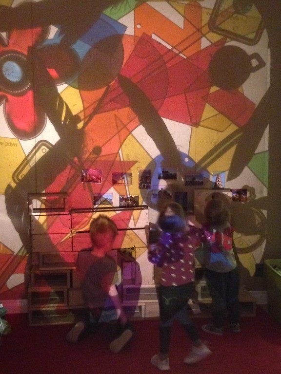 A group of children standing in front of a colorful wall
