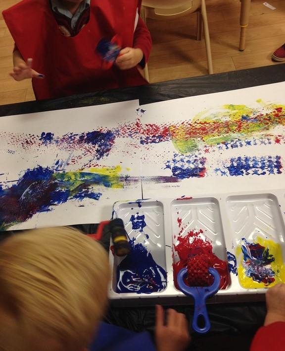 Two children are playing with paint on a table