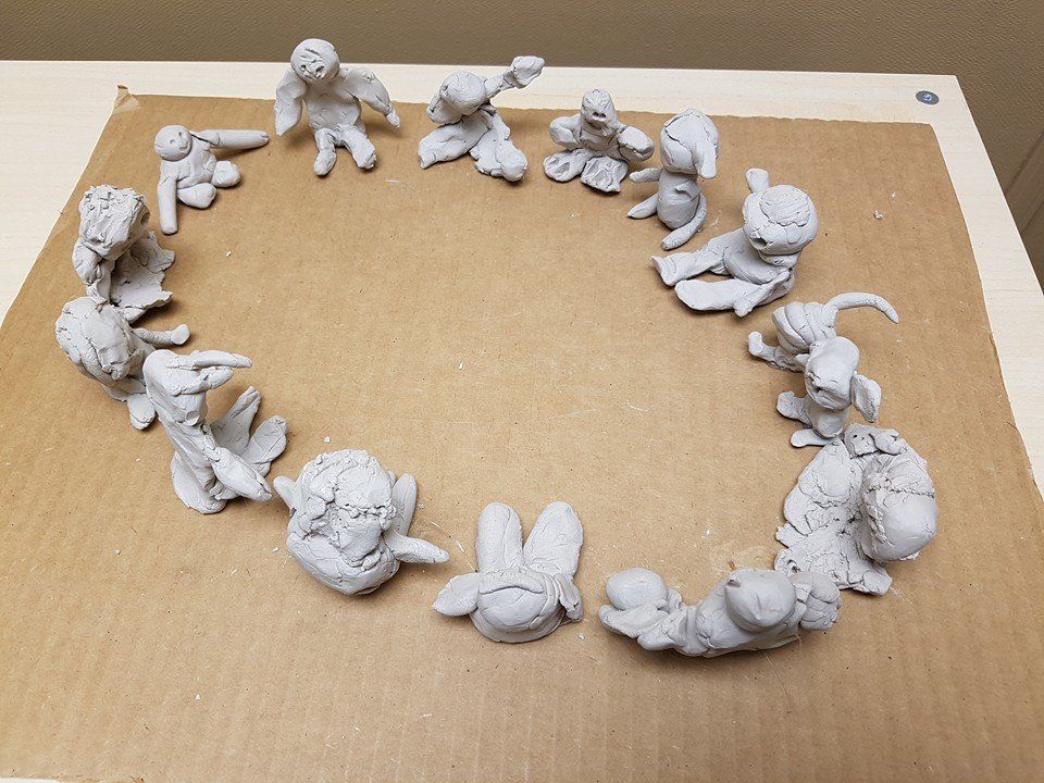 A group of clay figures are sitting in a circle on a table.