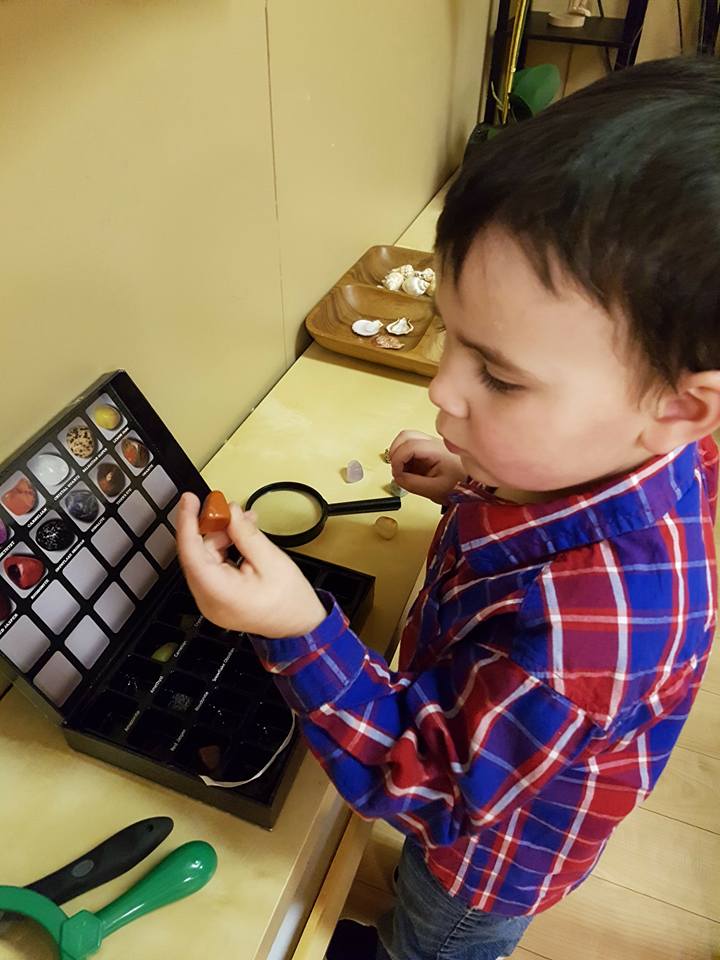A young boy in a plaid shirt is playing with a magnifying glass