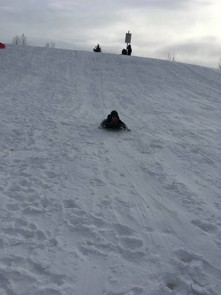 A person is sliding down a snow covered hill.