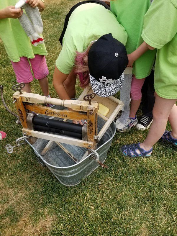 A group of people in green shirts are looking at a washing machine.