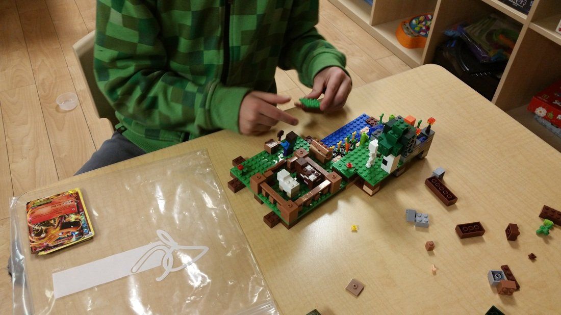 A child is sitting at a table playing with lego blocks.