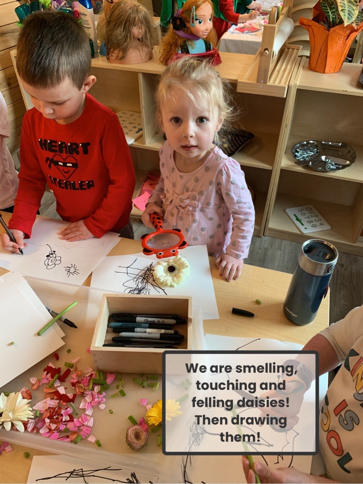 A group of children are sitting at a table playing with flowers.