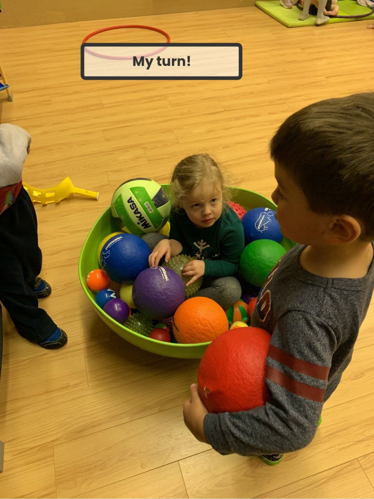A boy and a girl are playing with balls in a bowl with a sign that says my turn