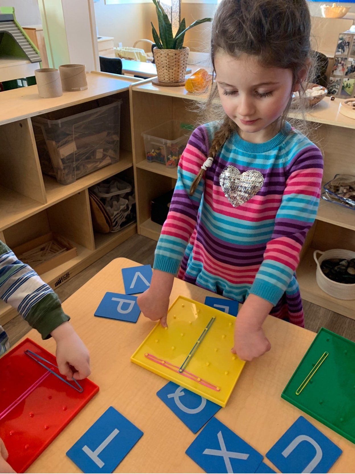 A little girl is playing with letters and numbers on a table