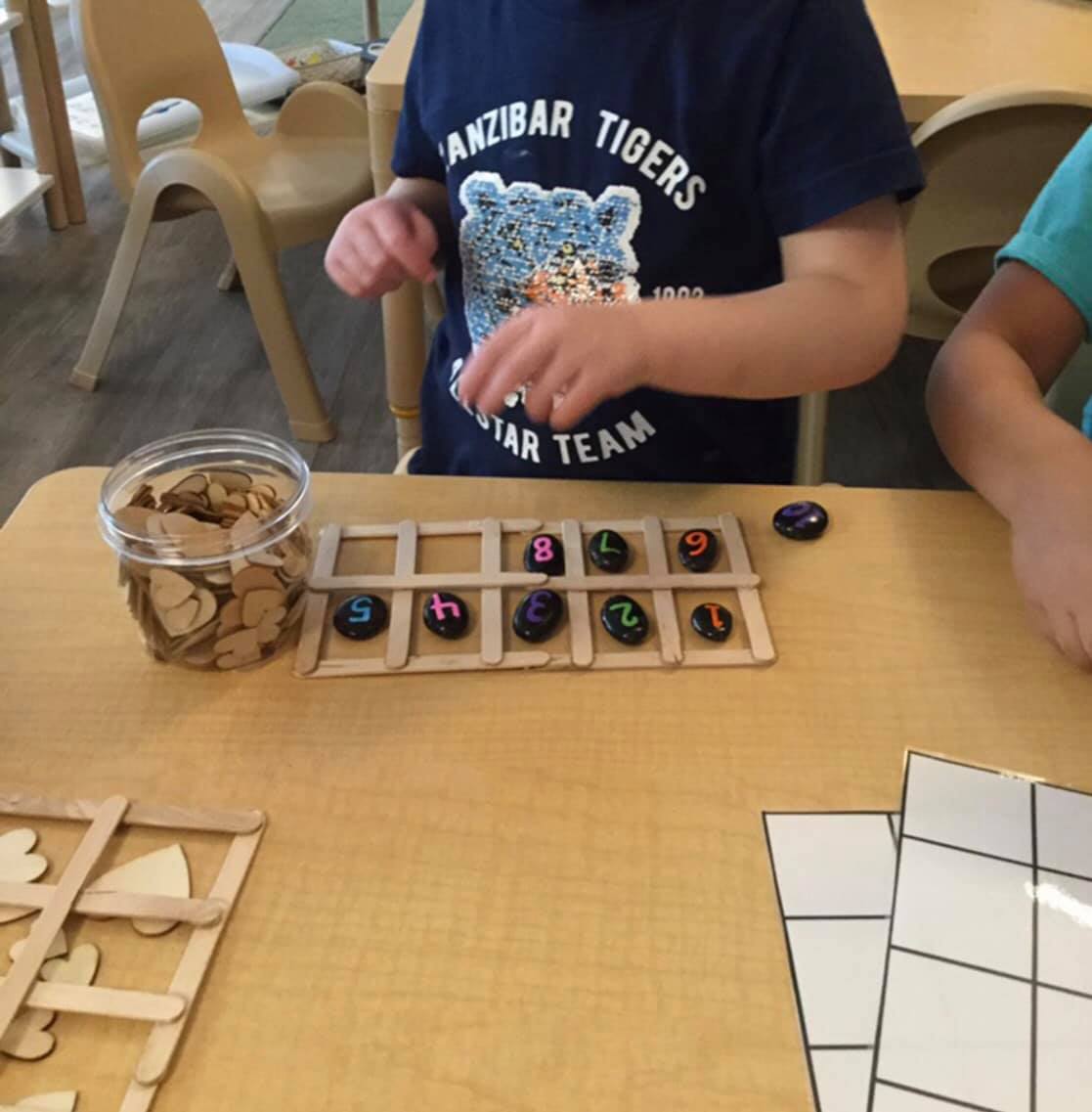A boy in a zanzibar tigers shirt sits at a table