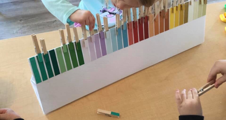A child is playing with a display of colored pencils on a table.