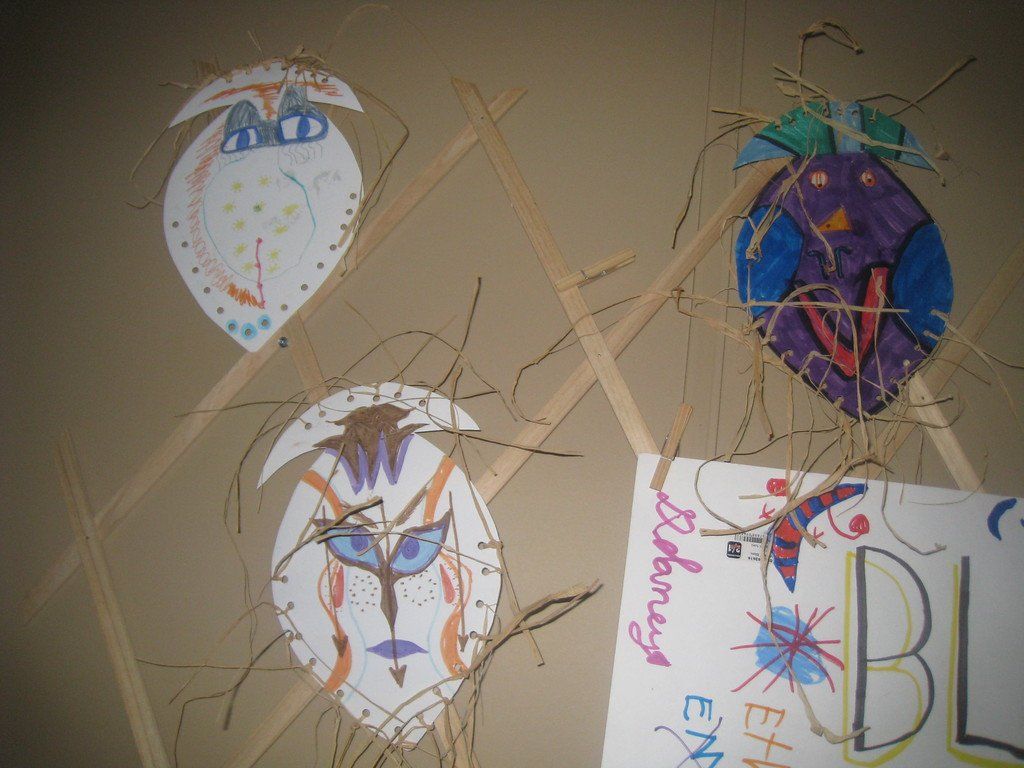 A bunch of kites are hanging on a wall and one of them has the word bunny on it