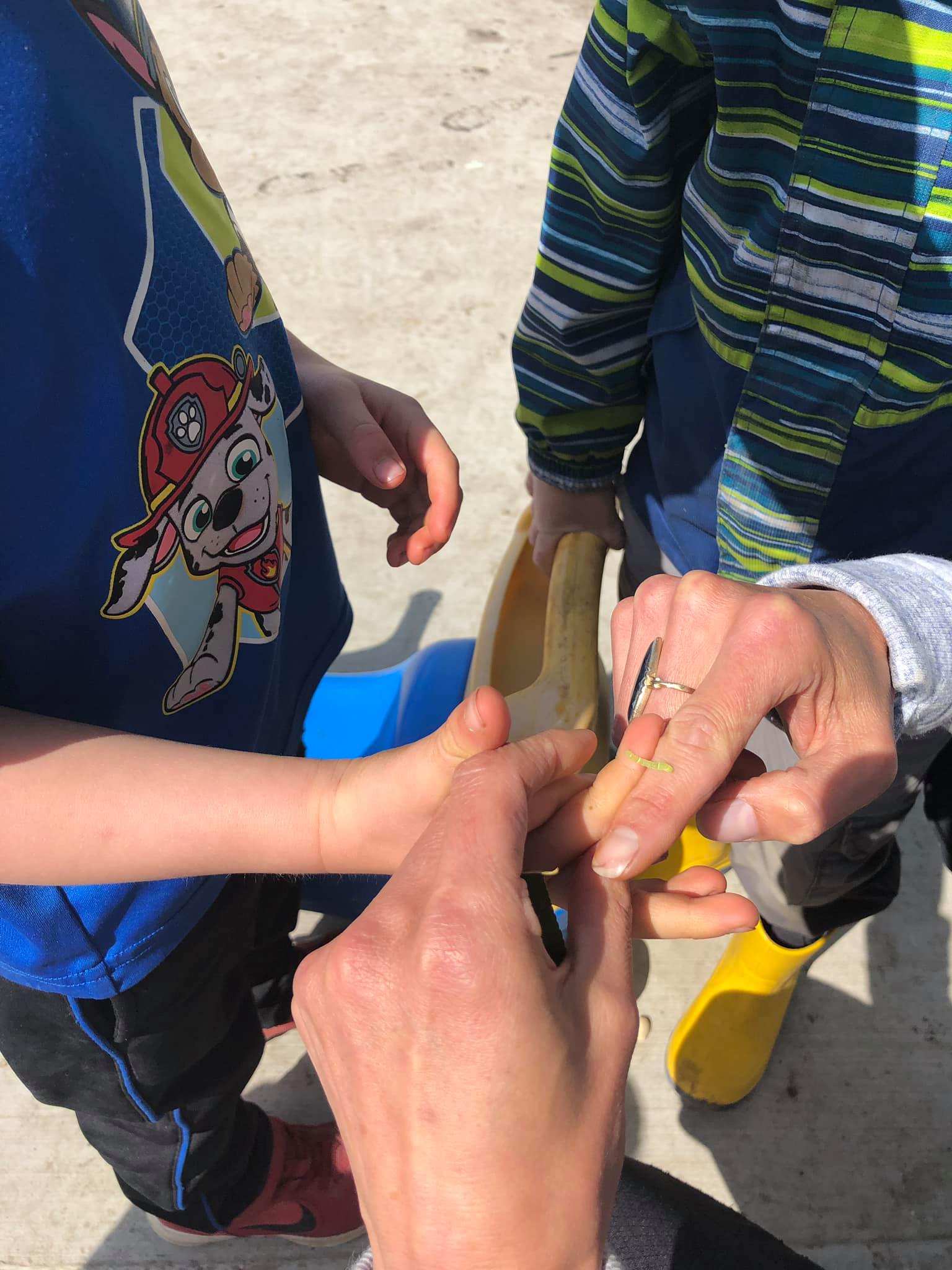 A person is peeling a banana on a child 's finger.