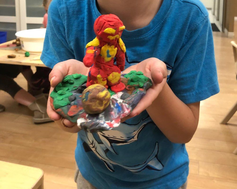 A child in a blue shirt is holding a clay figure