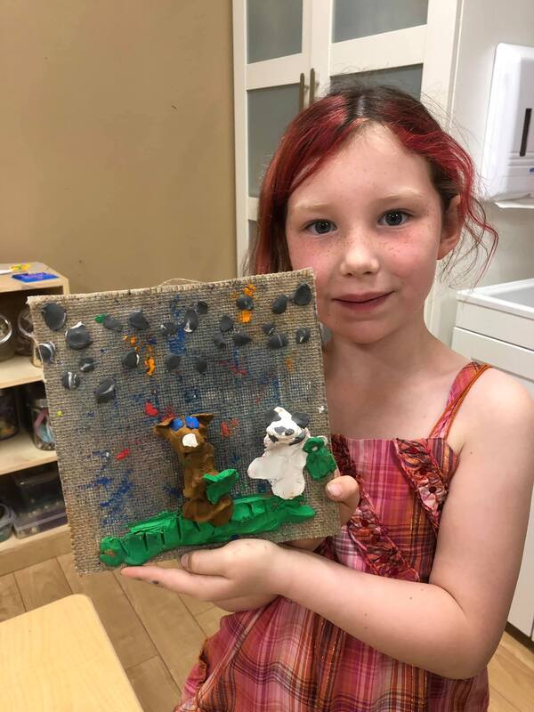 A young girl is holding a painting of a bear and a ghost.