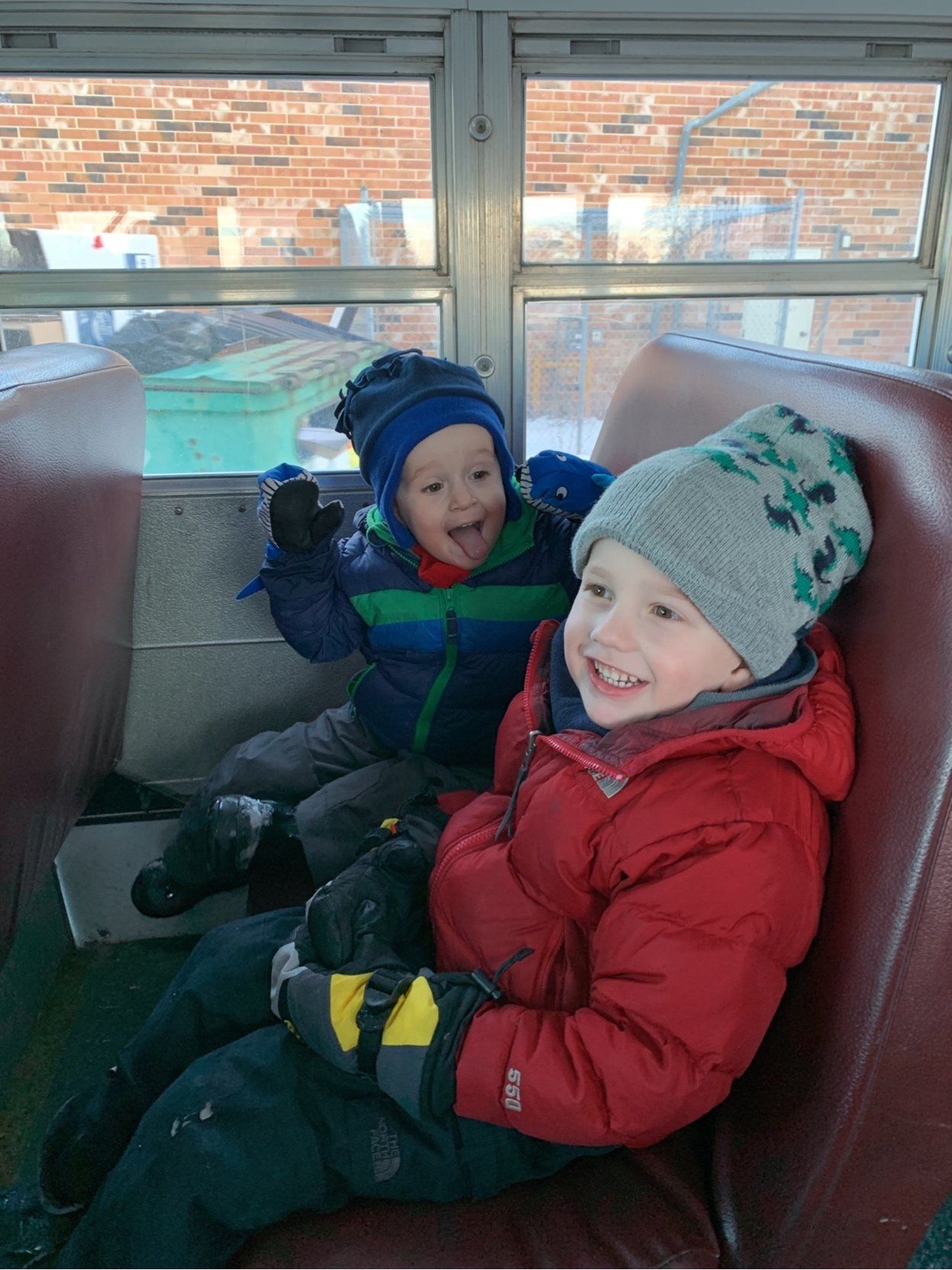 Two young boys are sitting on the back of a school bus