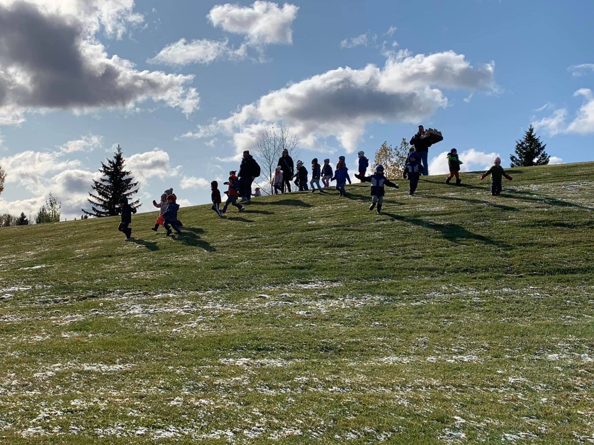 A group of children are playing on top of a grassy hill.