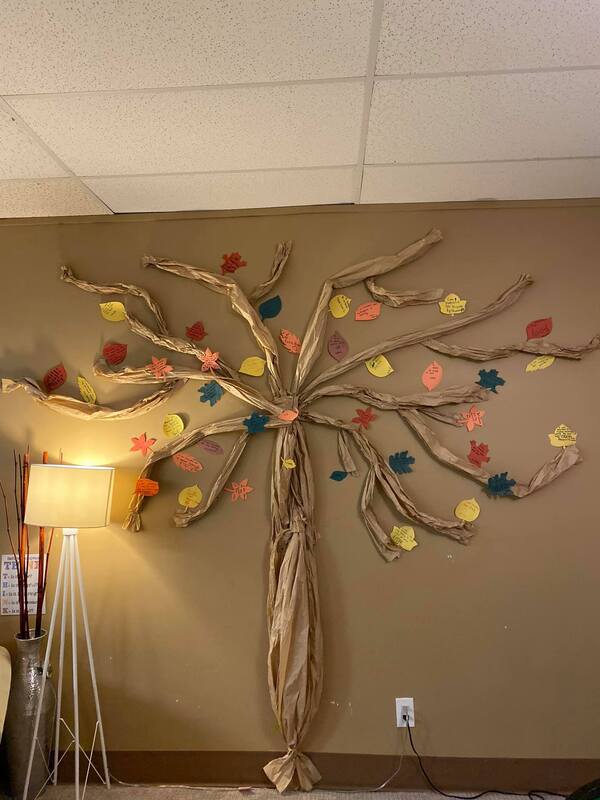 A tree made out of branches and leaves is hanging on a wall.