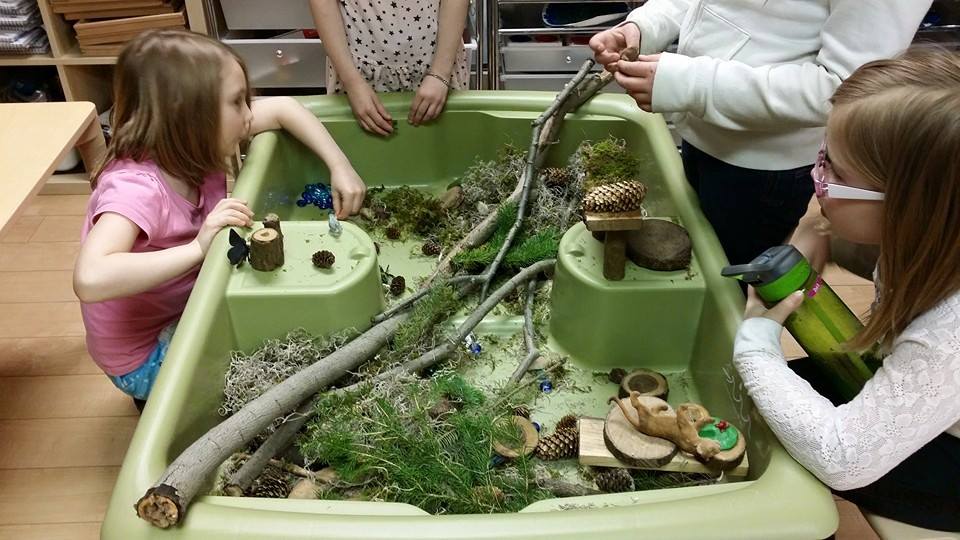 A group of children are playing in a sensory bin.