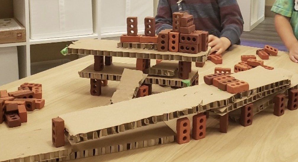 A child is playing with bricks on a cardboard table.