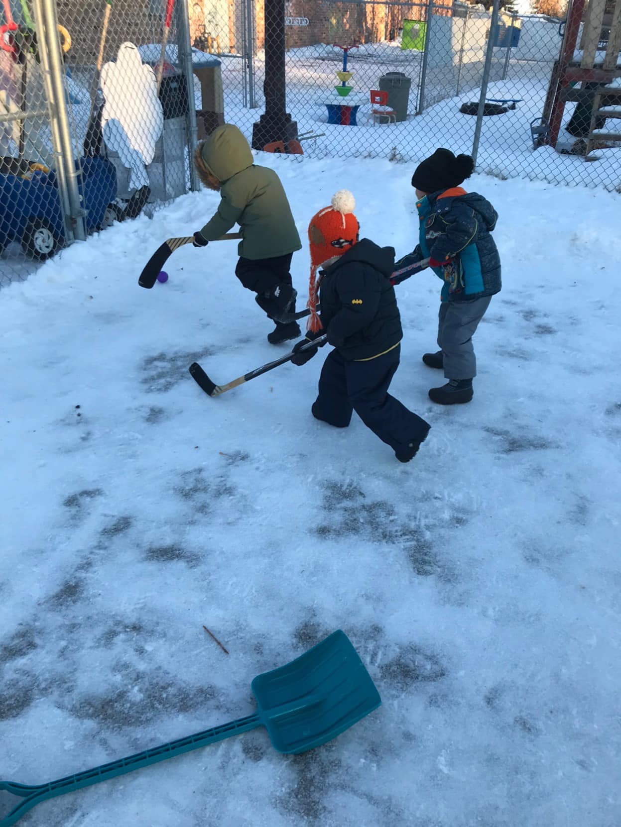 A group of children are playing hockey in the snow.