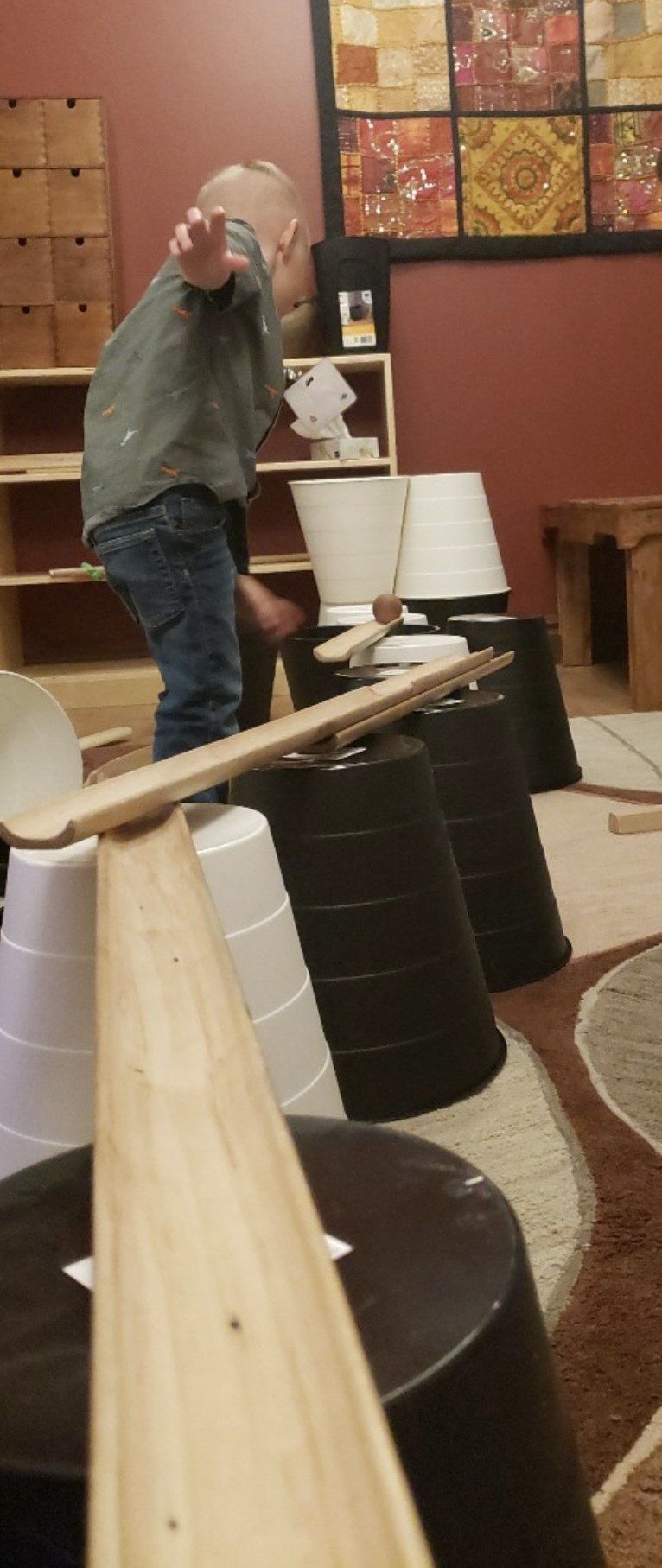 A young boy is playing with a wooden ramp in a room.