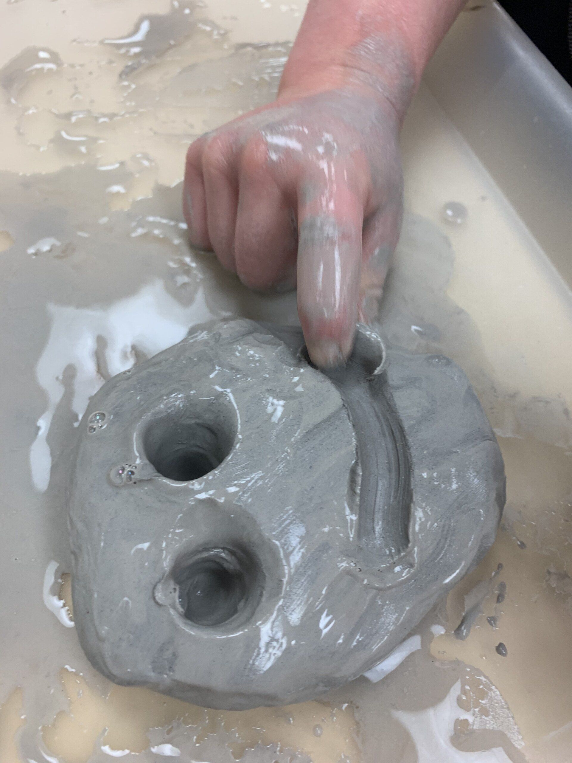 A person is holding a piece of clay in their hand.