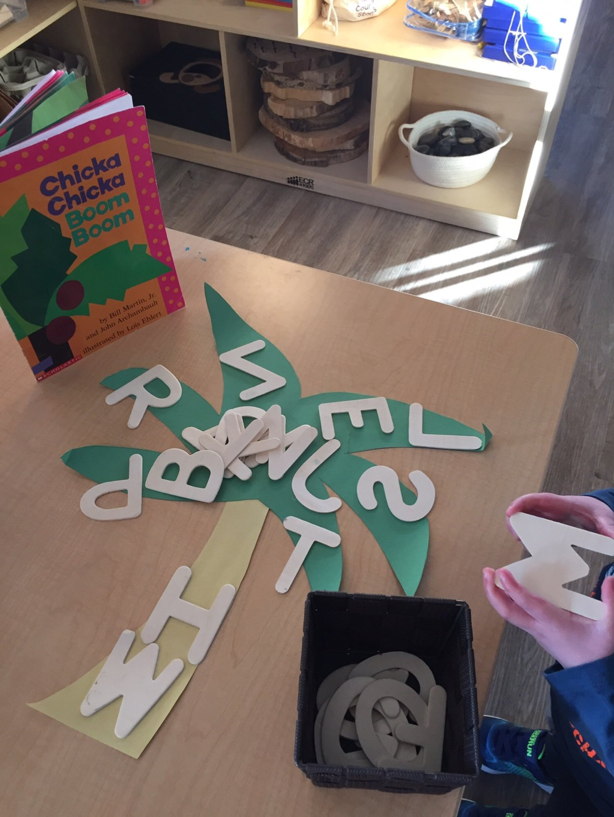 A child is playing with letters on a table in front of a book called chicken chicken chicken