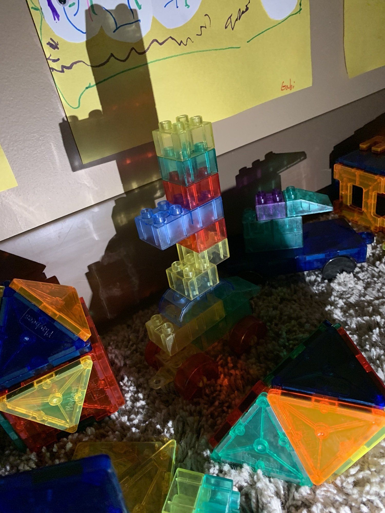 A bunch of colorful blocks are sitting on the floor next to a drawing on a wall.