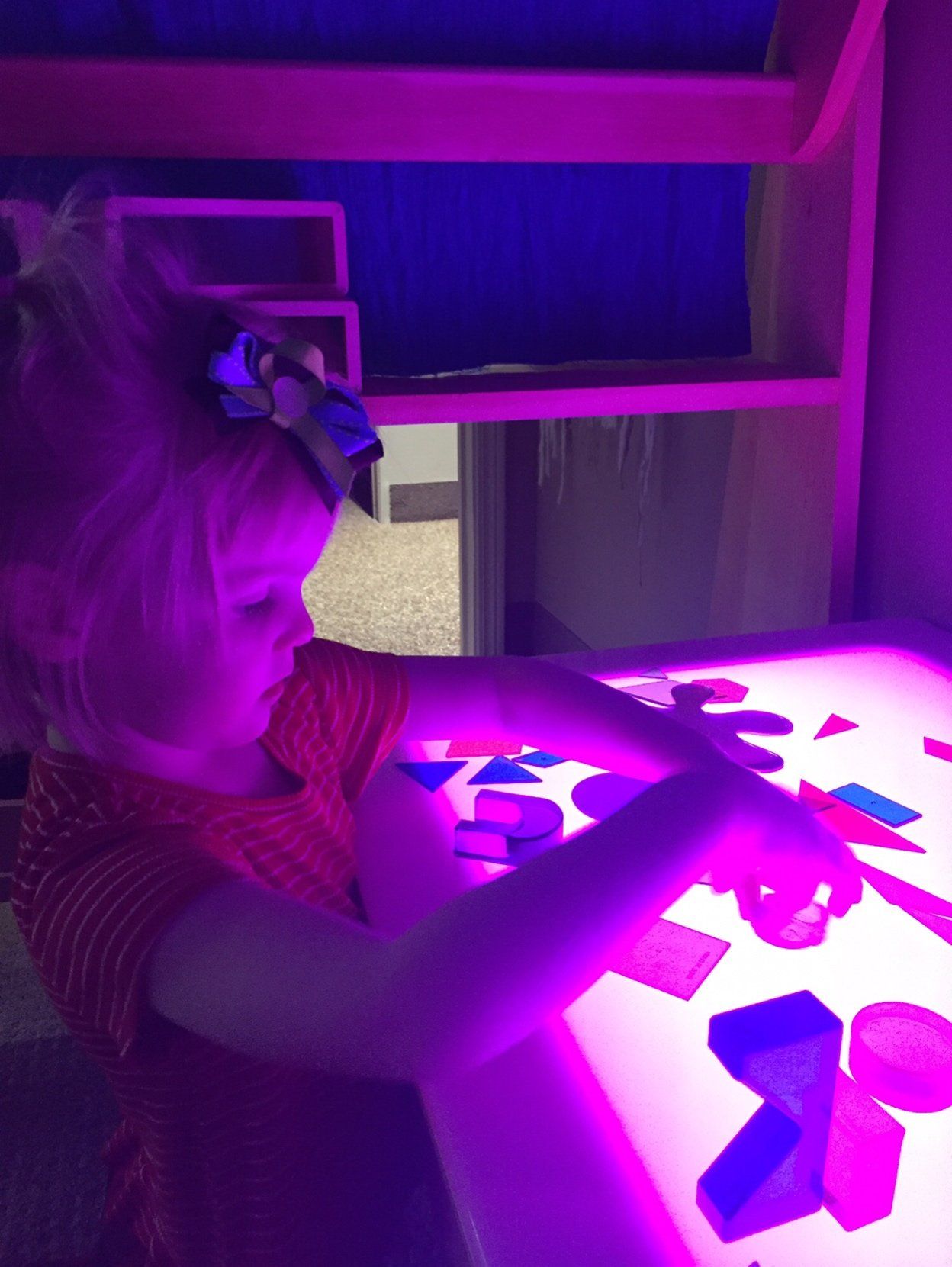A little girl is playing with purple lights on a table