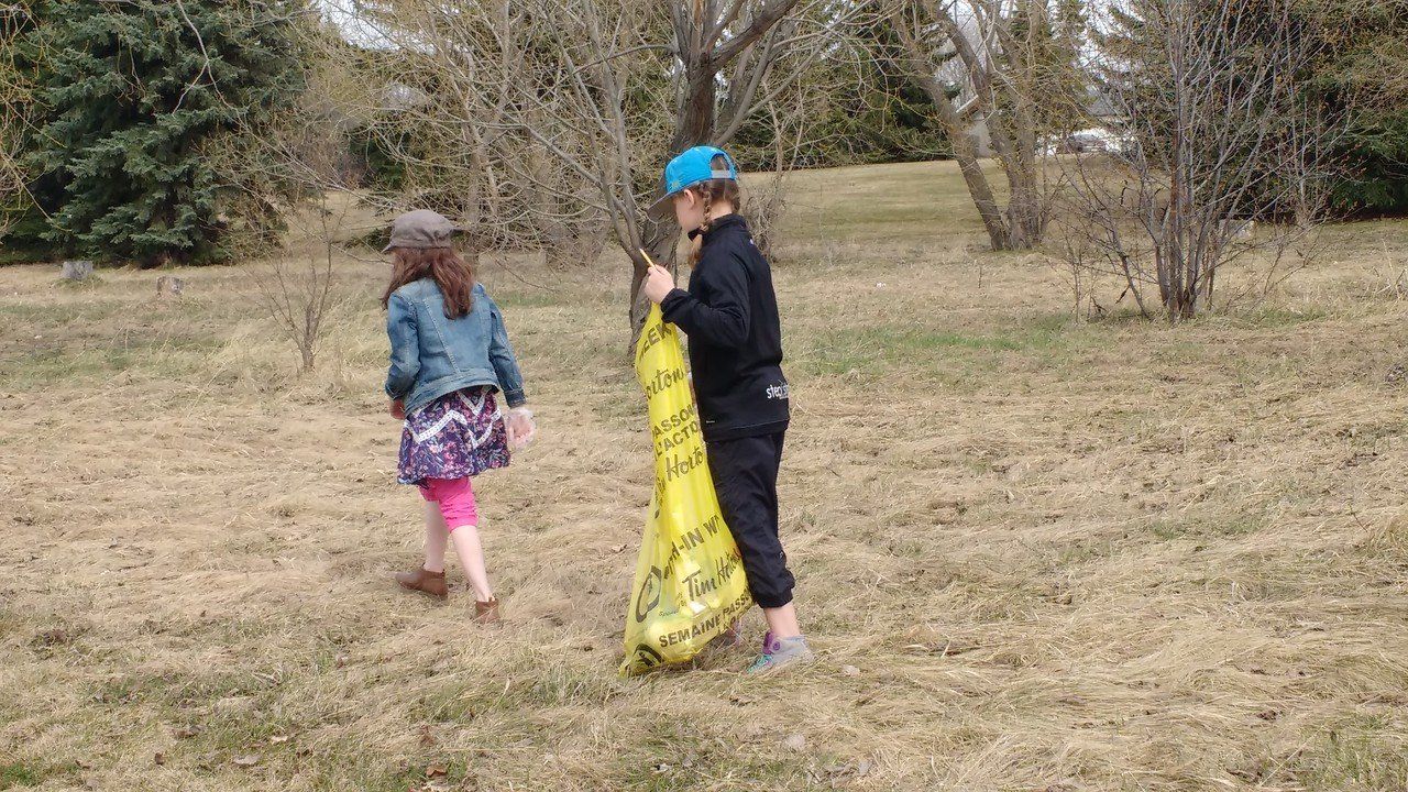 A boy and a girl are picking up trash in a park.