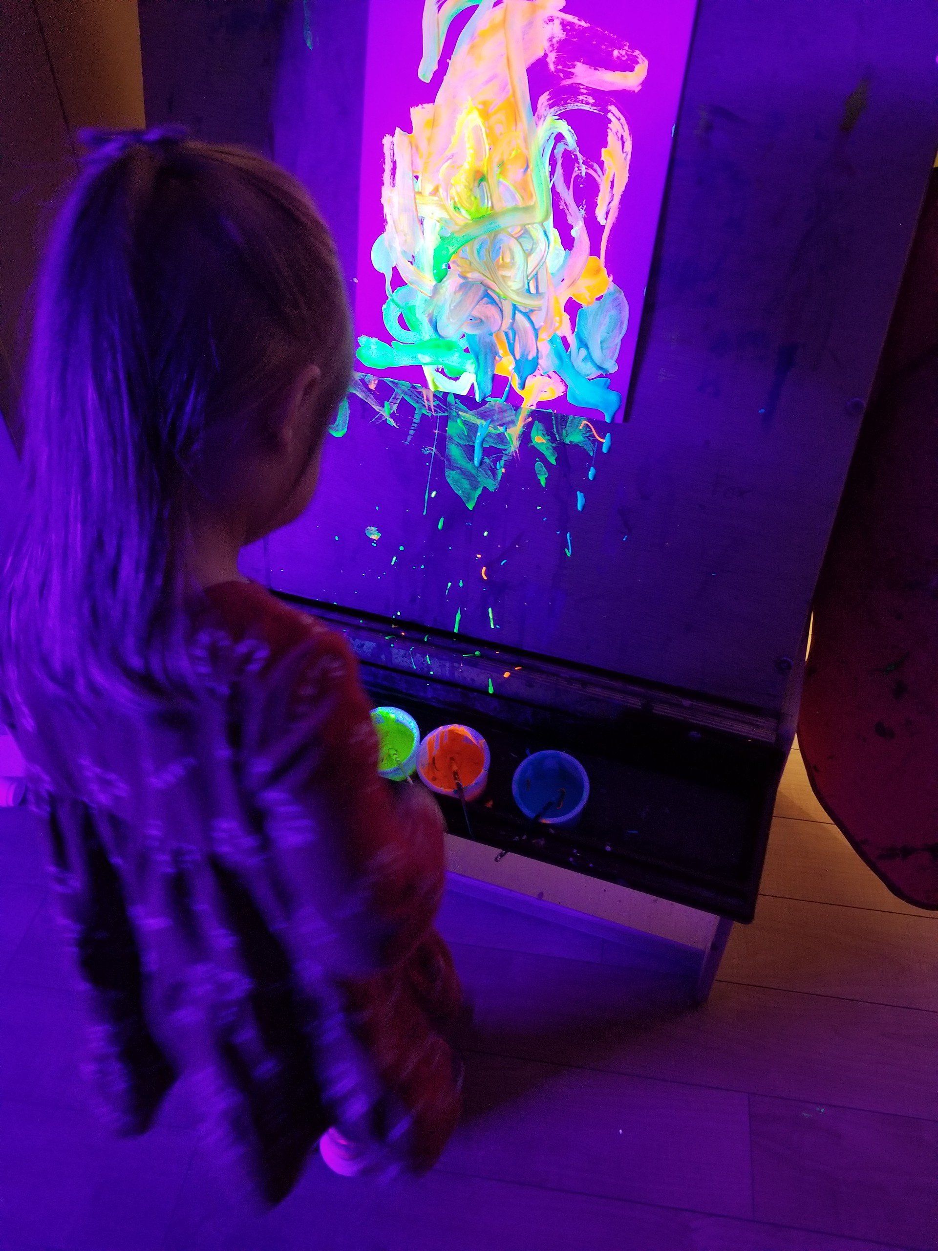 A little girl is playing with glow in the dark paint