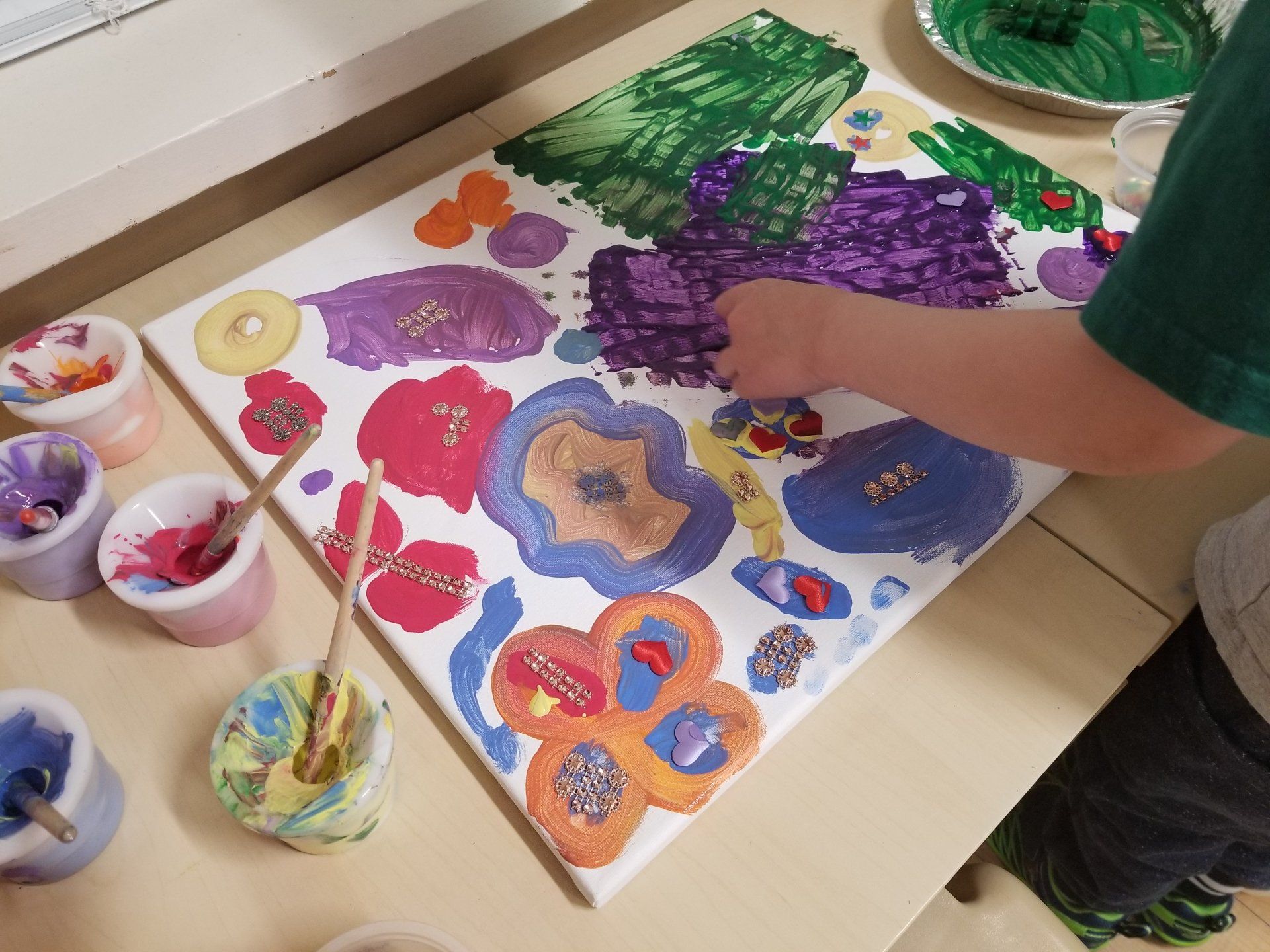 A child is painting flowers on a canvas on a table