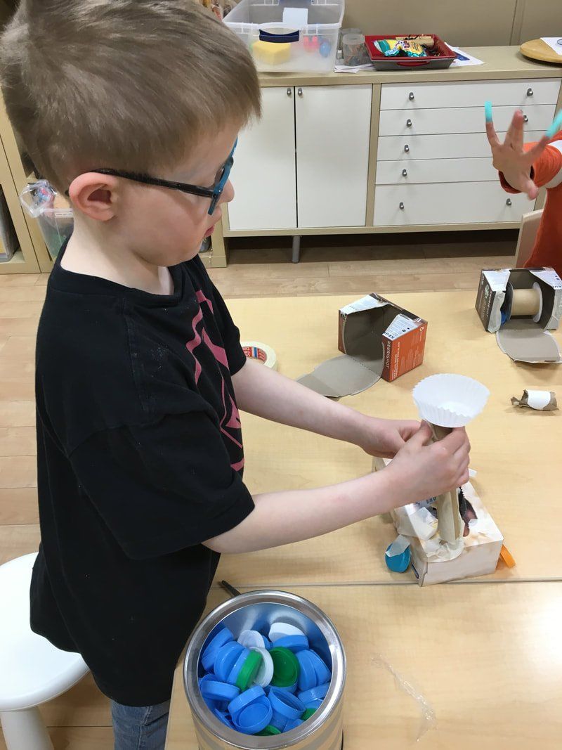 A young boy wearing glasses is playing with a toy on a table.