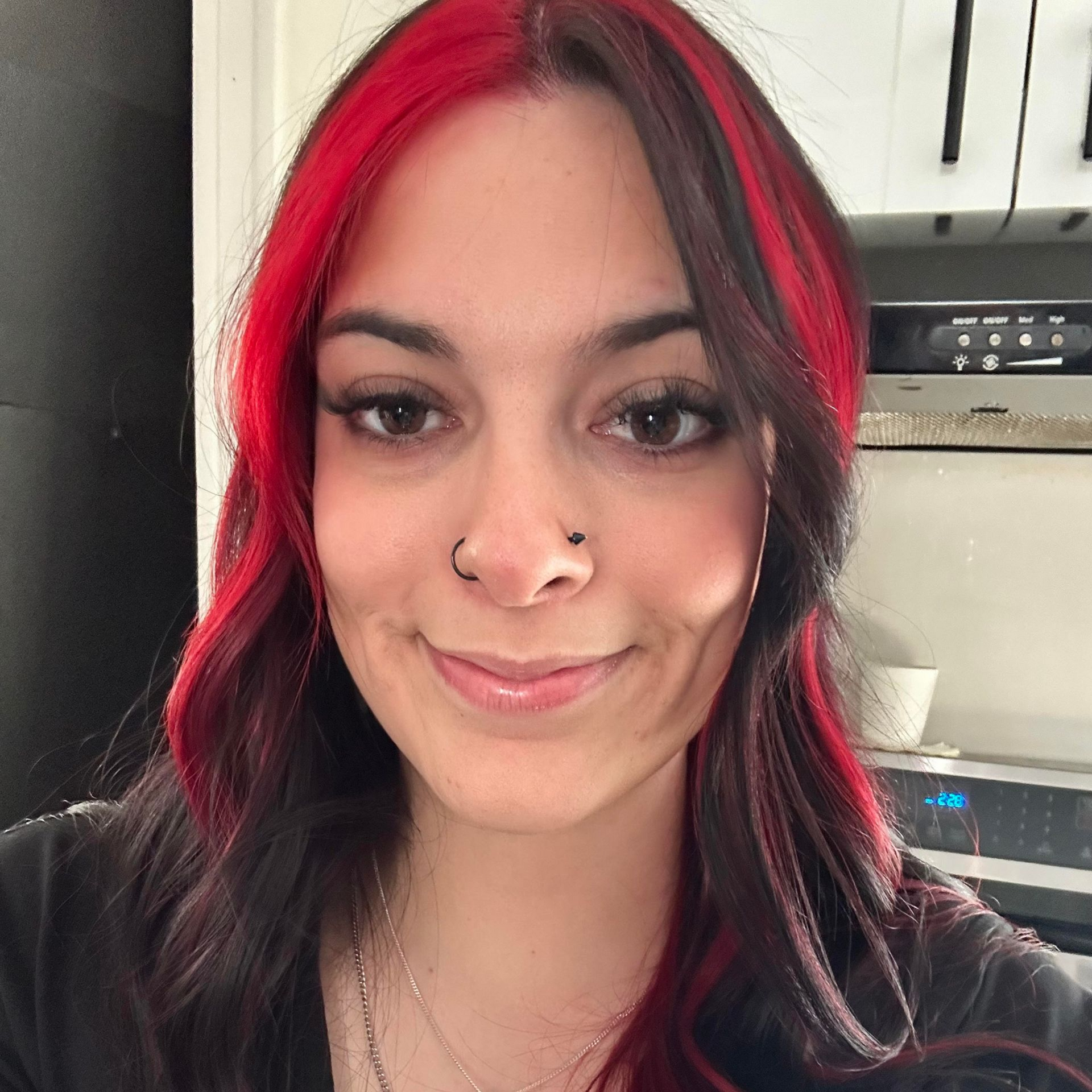 A woman wearing a pink shirt and hoop earrings is smiling for the camera.