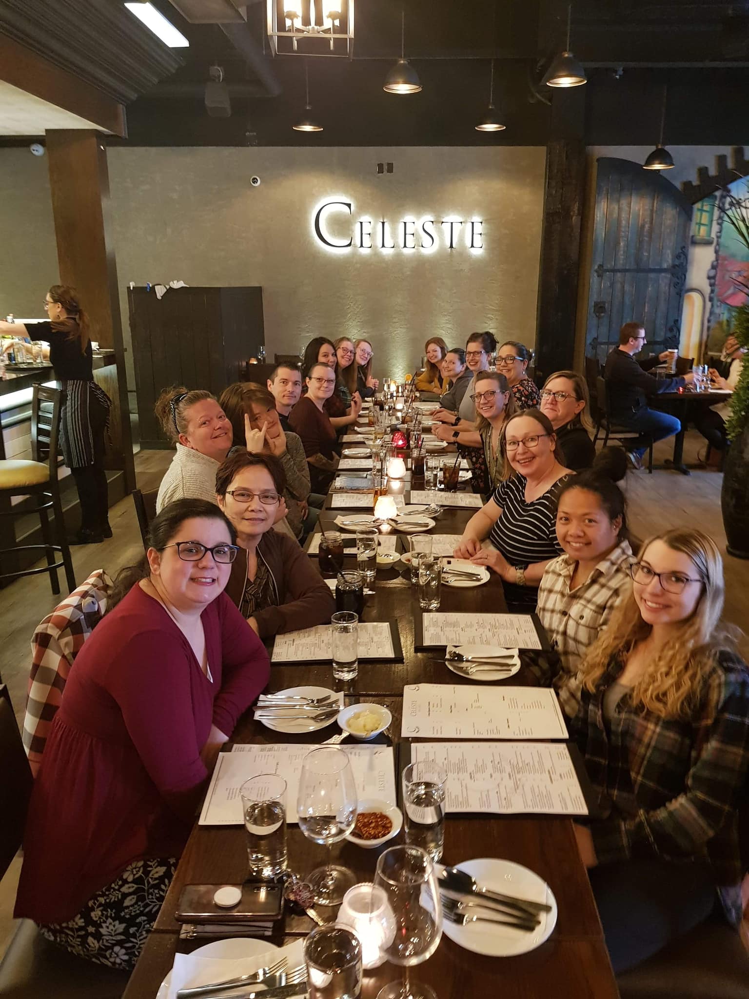 A group of people are sitting at a long table in a restaurant.
