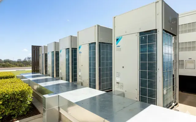 A row of large, light-colored Daikin industrial air conditioning units on a building rooftop.