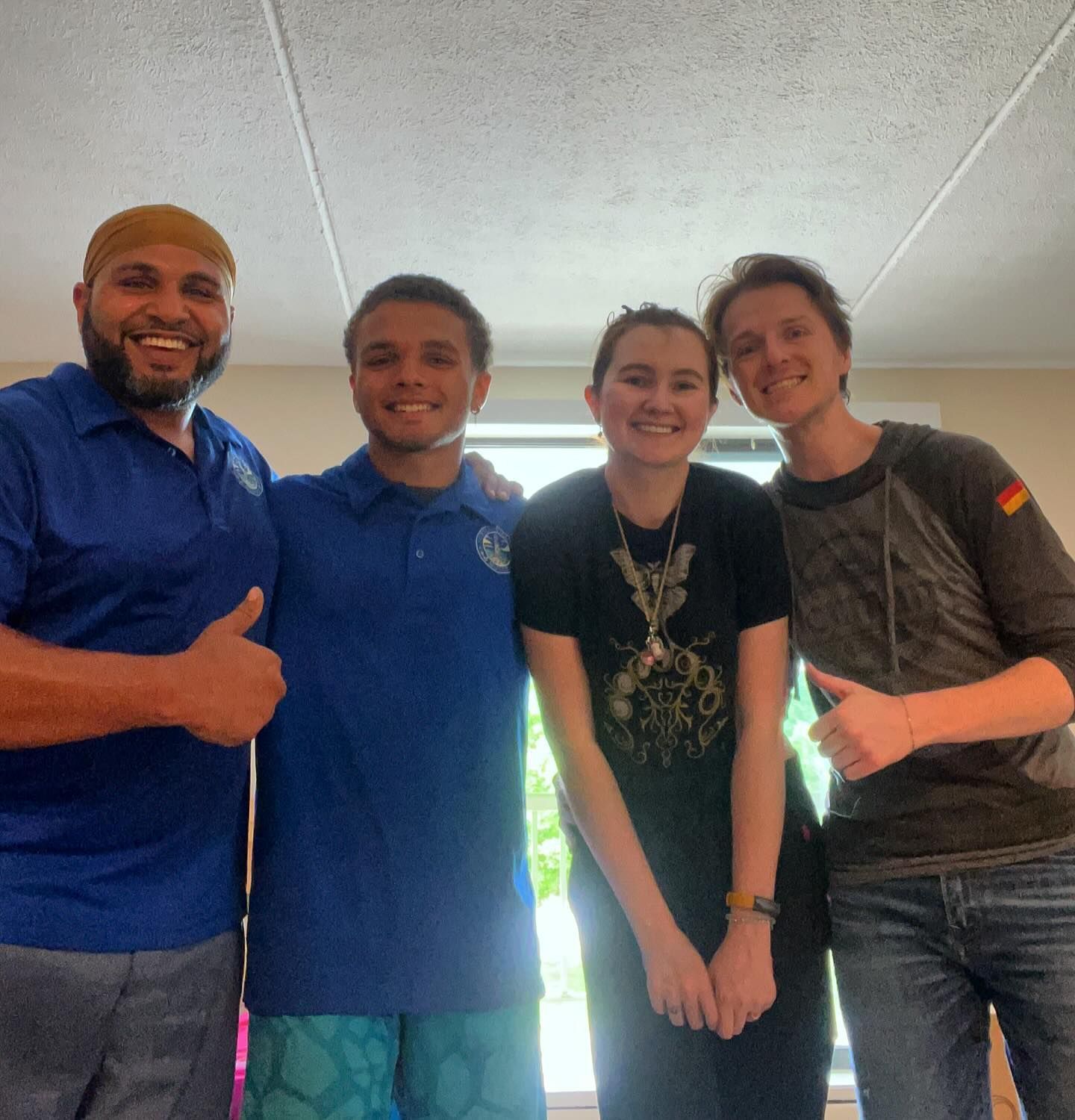 Four people smiling and posing indoors.
