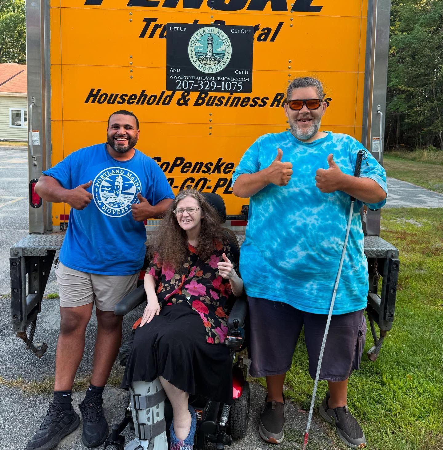 Three people in front of a Penske truck, giving thumbs up. One uses a wheelchair, one uses a cane, and one is standing.