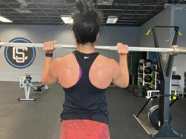 A Woman Is Lifting A Barbell - Chicago, IL - Fast Track Physio