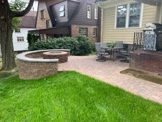 Backyard patio with stone steps, pond, bench, and white fence.