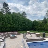 Backyard patio with fire pit, seating, and landscaping in a residential setting.