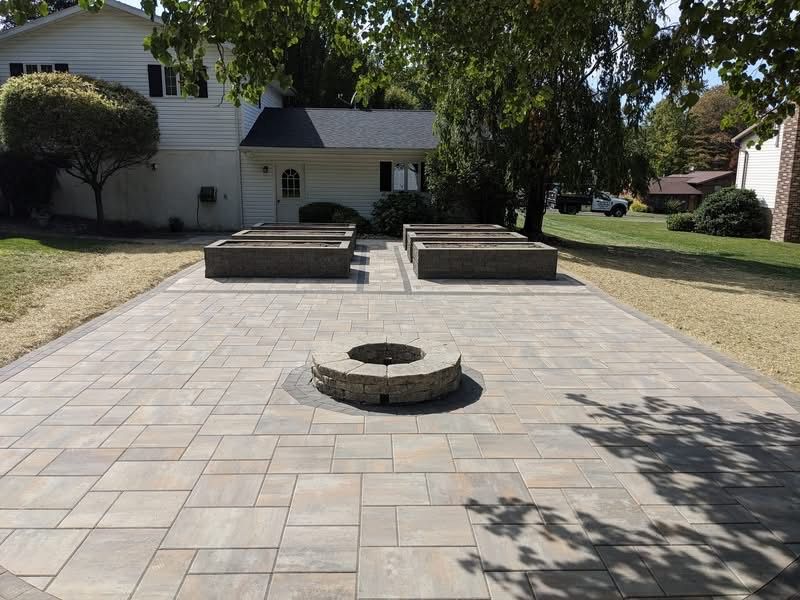 A backyard patio with rectangular pavers, fire pit, and raised garden beds.