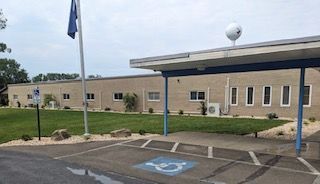 Stone steps leading up to a house with a brick facade and landscaping, featuring a small American flag.