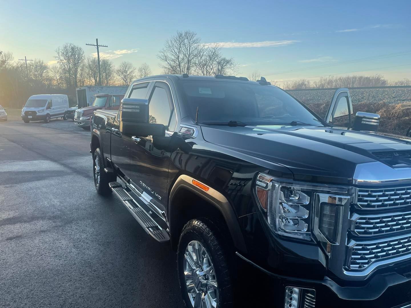 Black GMC truck parked outdoors on a paved lot on a sunny day.