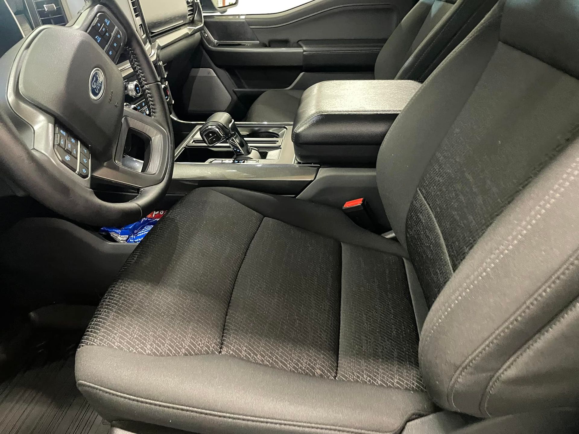 Interior of a black Ford truck. Front driver's seat, dashboard, steering wheel, and console are visible.