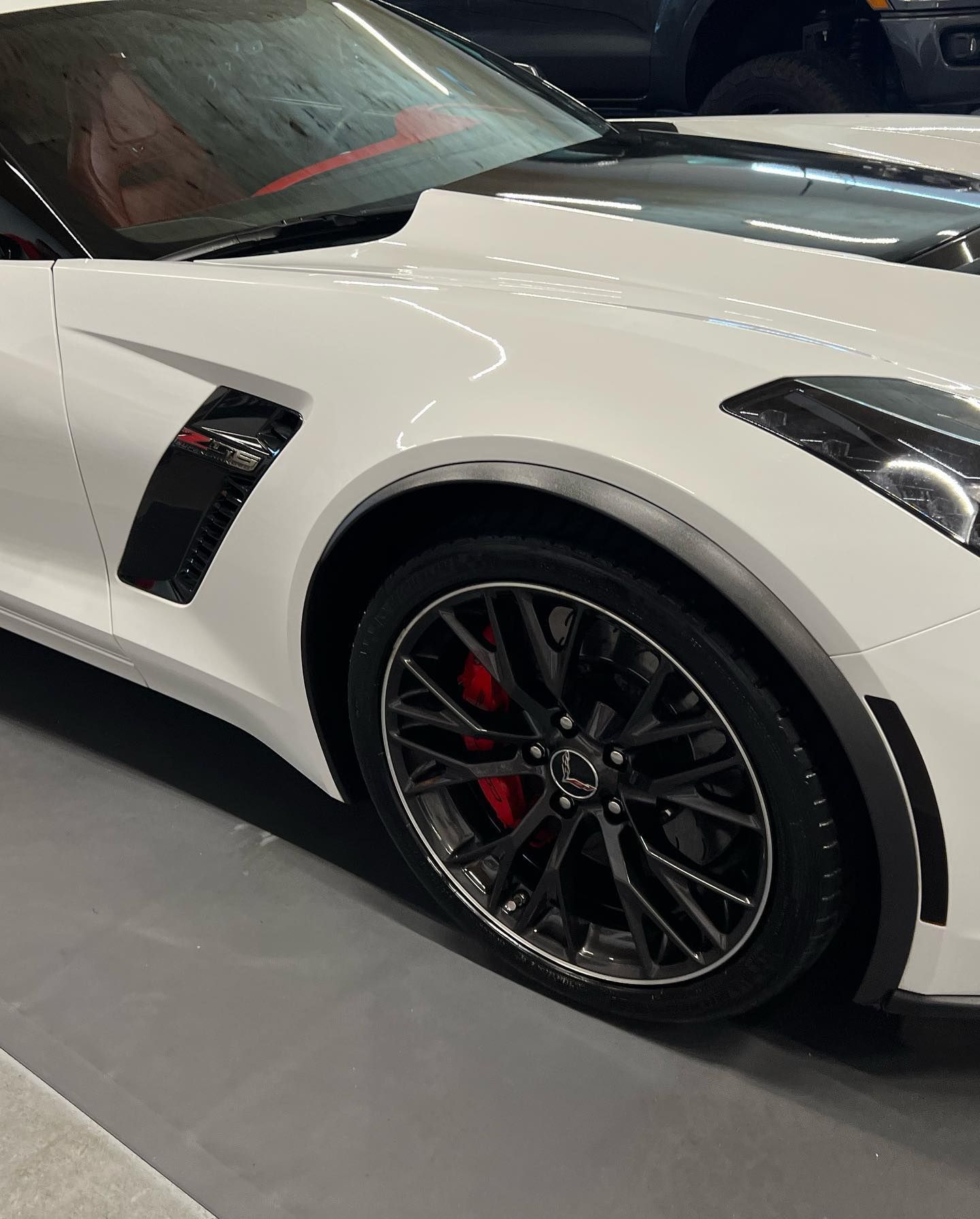 White sports car with black wheels and red brake calipers.