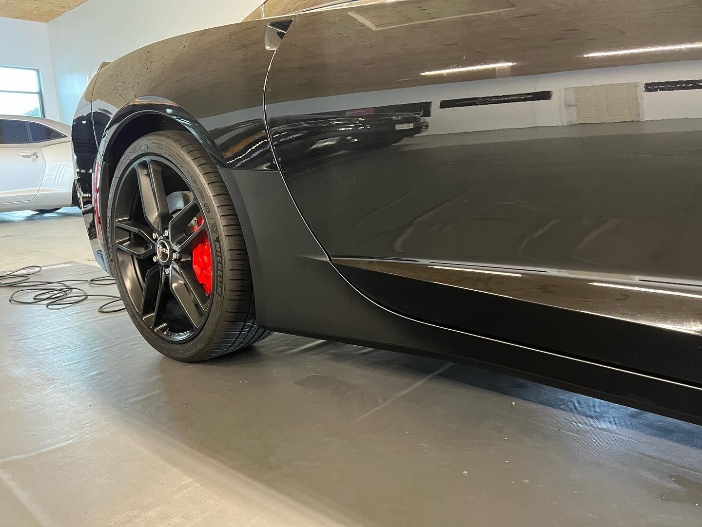 Black sports car with red brake calipers, parked indoors.