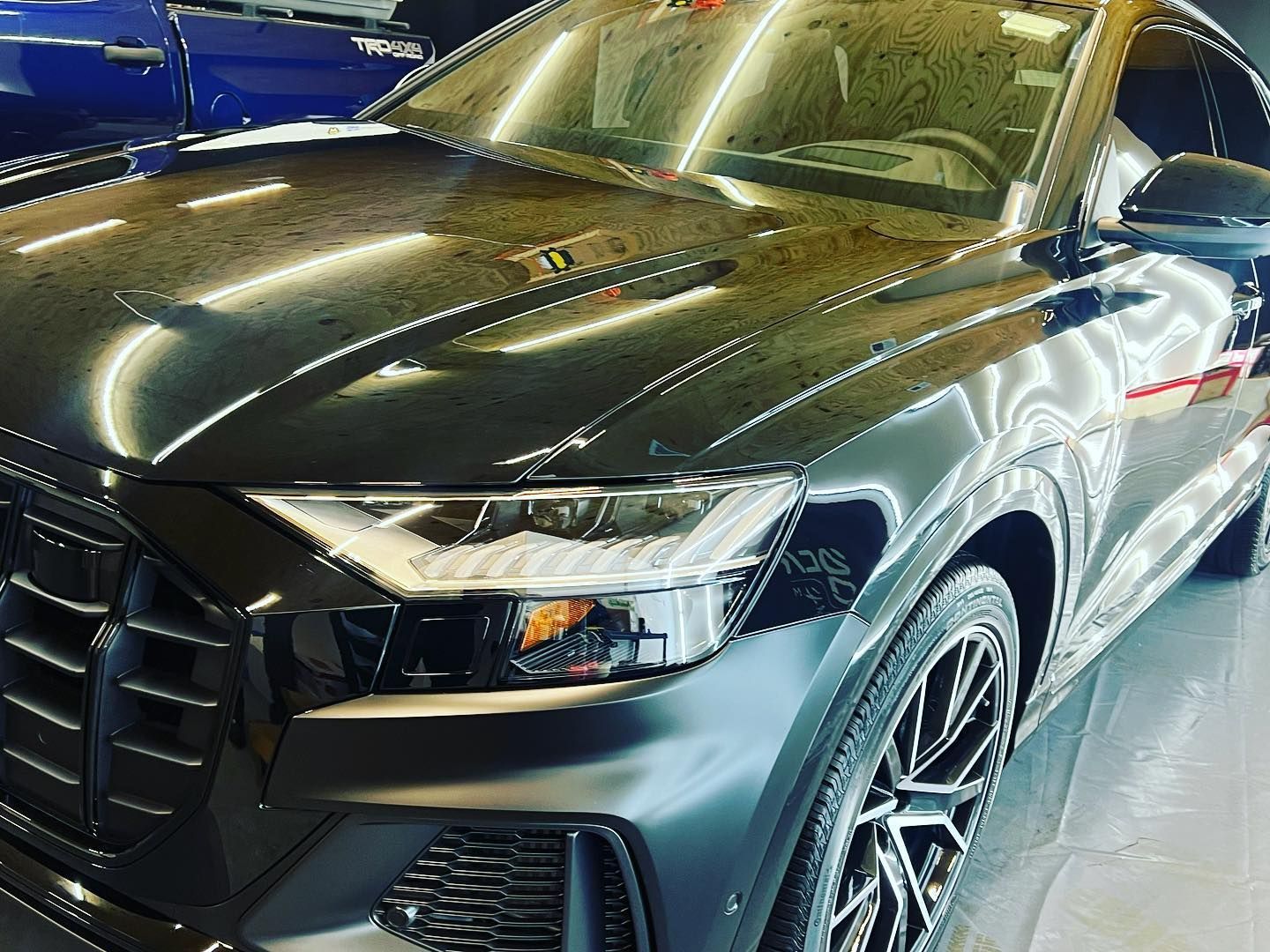 Black Audi SUV with shiny paint, parked in a showroom.
