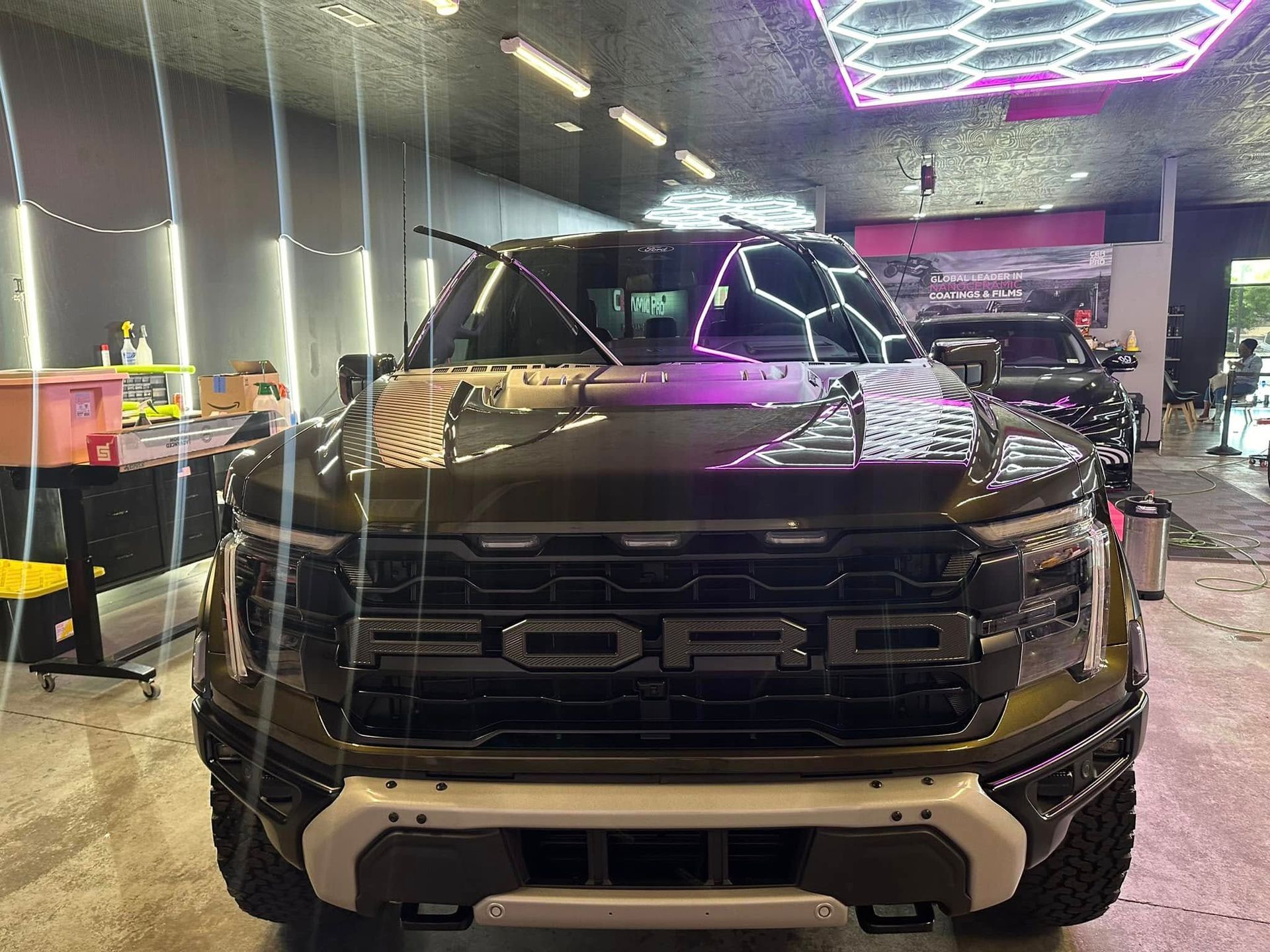 Ford Raptor truck, front view, in a shop with lighting.