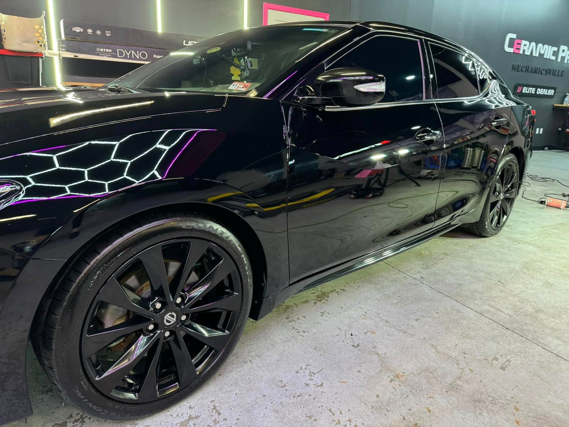 Black car with tinted windows and black rims in a garage.
