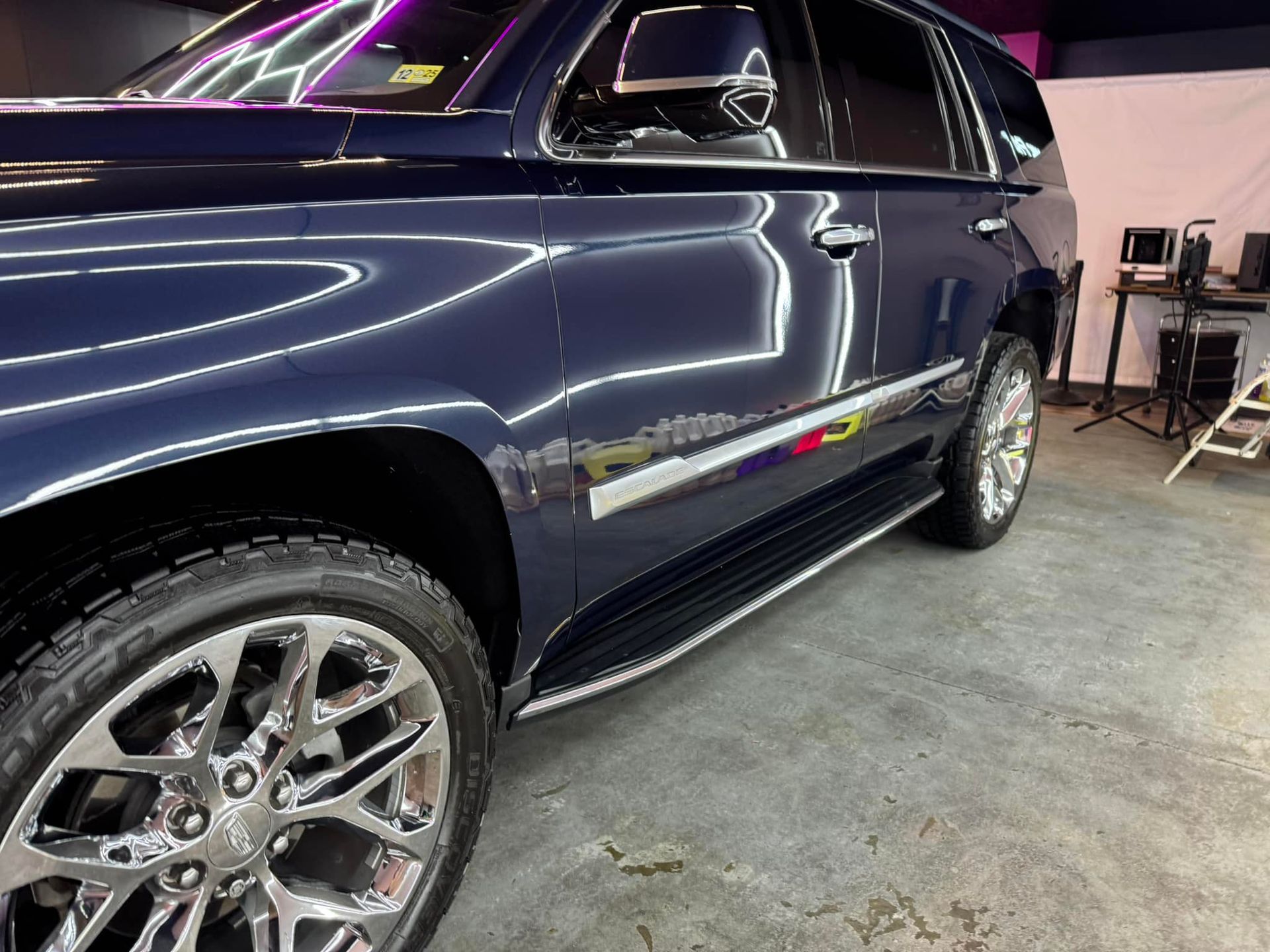Blue SUV with chrome wheels and trim parked indoors.