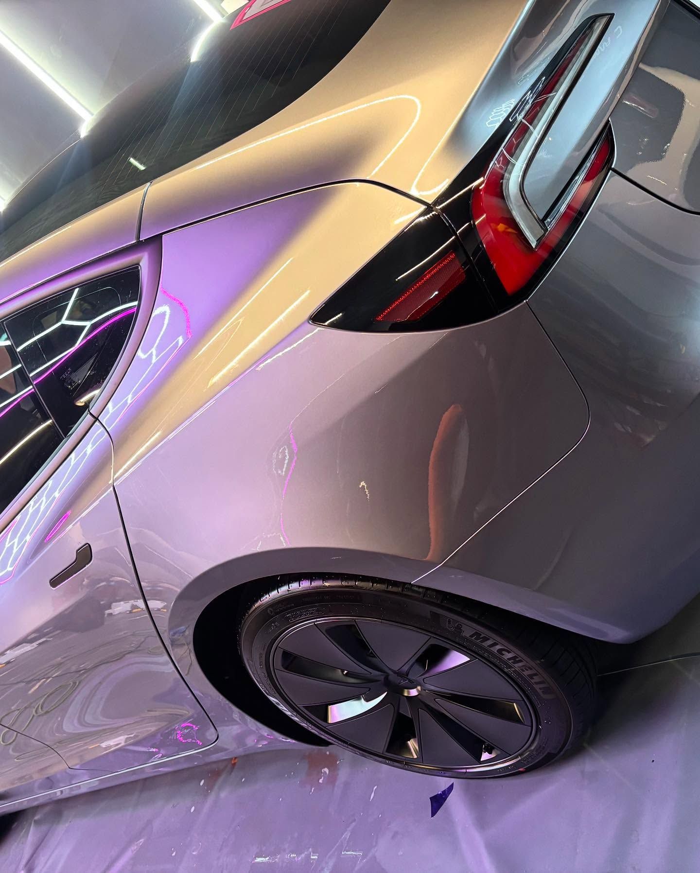 Silver Tesla car rear side, black wheel and tail light details.